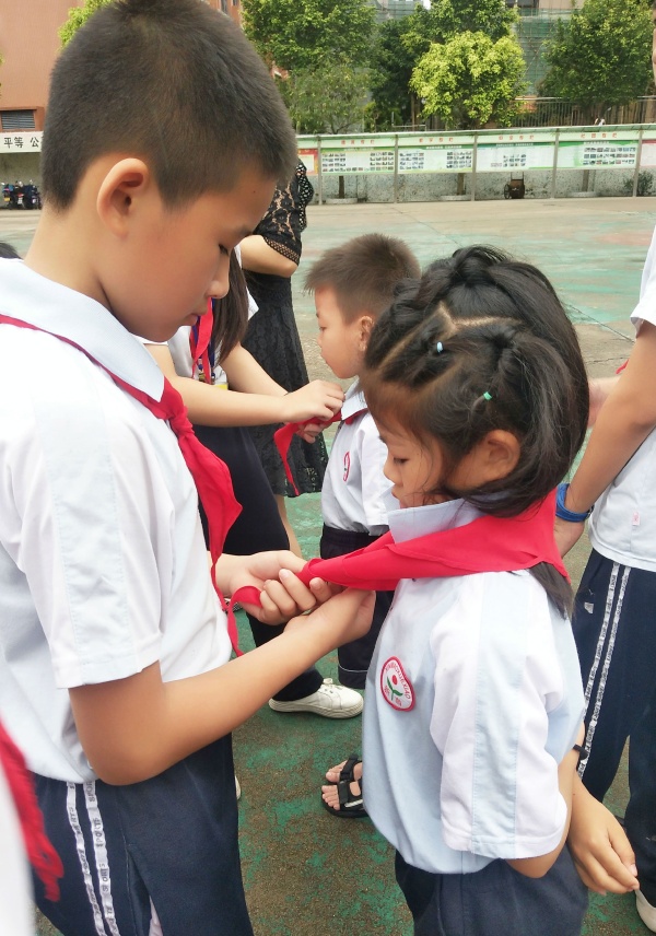 老隊員為新隊員佩戴紅領(lǐng)巾